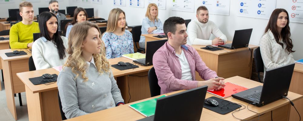Grupo de alumnos atiende una clase de formación con ordenadores portátiles.